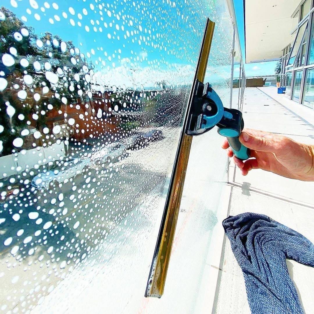 Squeegee gliding across a soapy window mid-clean